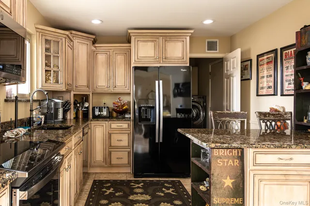 a kitchen with stainless steel appliances granite countertop a refrigerator a stove and a sink