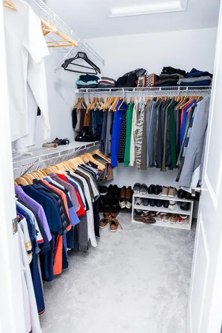 a view of walk in closet with clothes and shoes