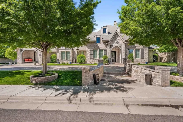 a front view of a house with a garden and tree