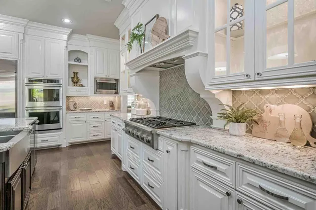a kitchen with granite countertop a stove a sink and a refrigerator