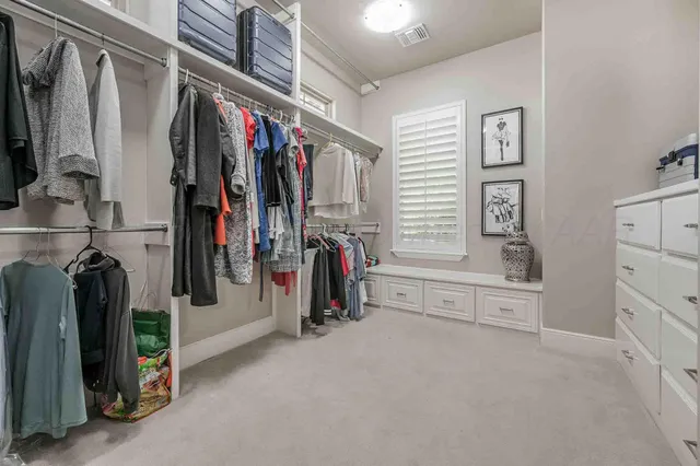 a view of walk in closet with clothes and shoes