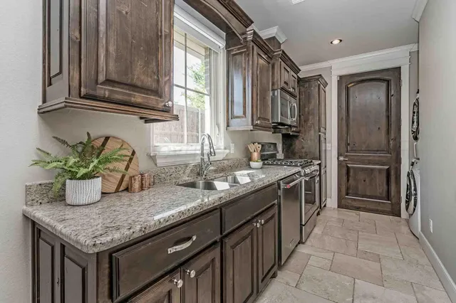 a kitchen with granite countertop kitchen island wooden cabinets stainless steel appliances a sink and a window