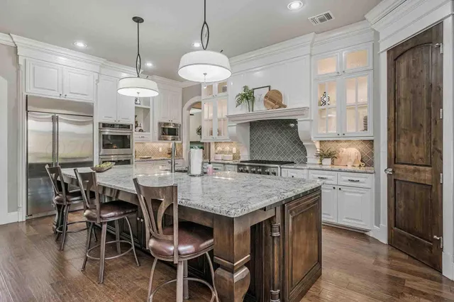 a kitchen with stainless steel appliances granite countertop a kitchen island a stove a table and chairs in it
