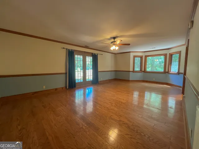 an empty room with wooden floor and windows