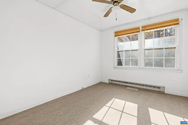 an empty room with chandelier fan and windows