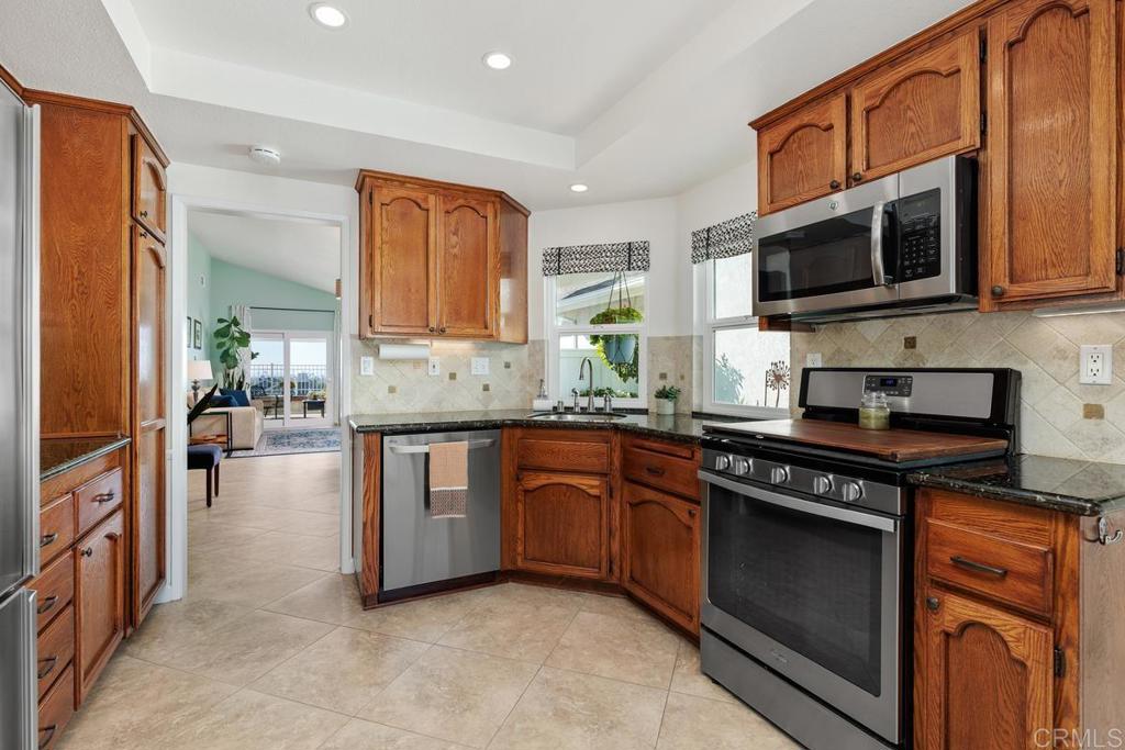 6833 Watercourse Drive Carlsbad, CA 92011 - Photo 7 of 49 a kitchen with stainless steel appliances granite countertop a stove microwave and sink