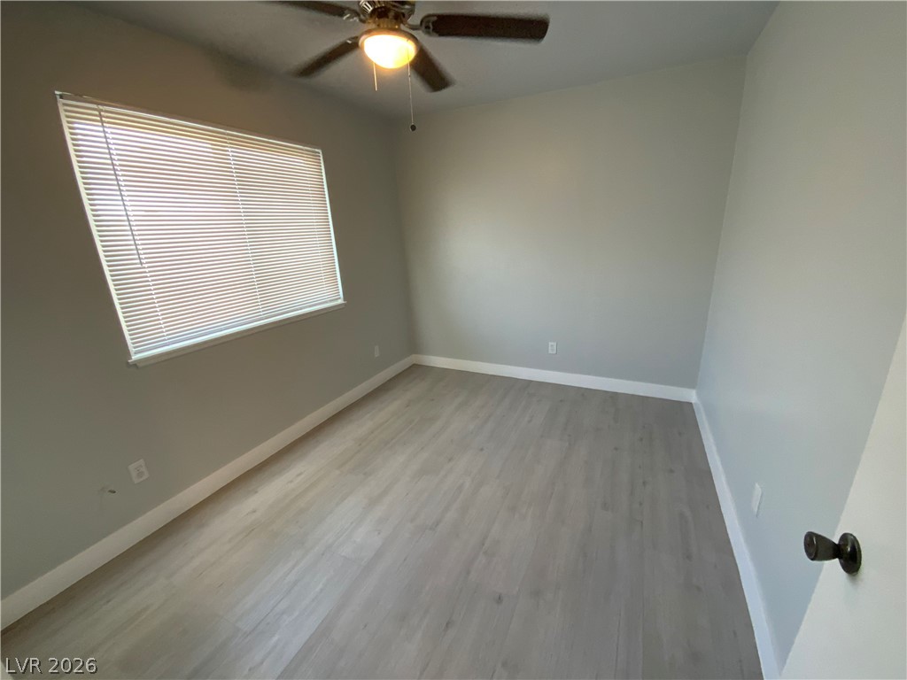 466 East Sunset Road, Unit C Henderson, NV 89011 - Photo 8 of 12 Unfurnished room featuring ceiling fan, baseboards, and wood finished floors