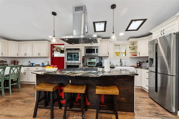 a kitchen with stainless steel appliances kitchen island a white table and chairs in it