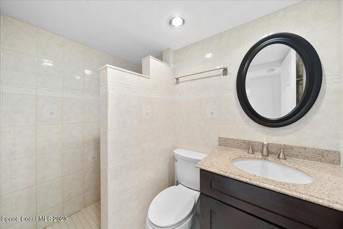 2020 North Atlantic Avenue, Unit 505 Cocoa Beach, FL 32931 - Photo 11 of 16 a bathroom with a granite countertop toilet sink and mirror
