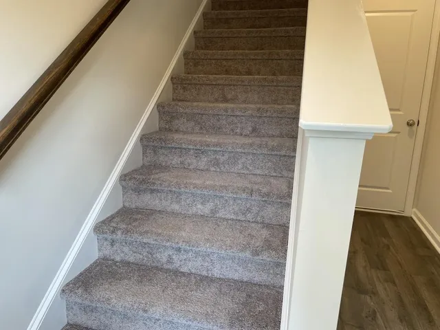 a view of staircase with white walls and white door
