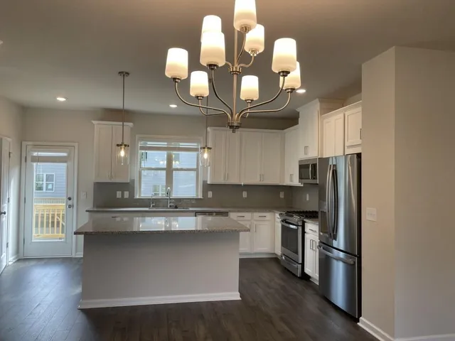 a kitchen with stainless steel appliances granite countertop a sink a stove and refrigerator