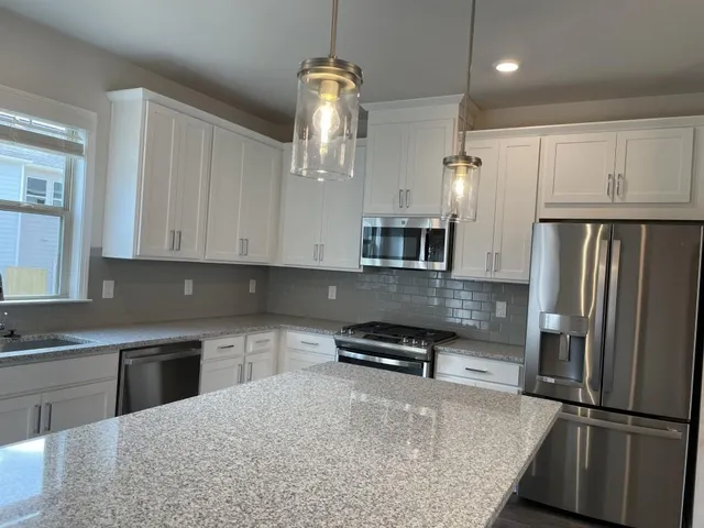 a kitchen with stainless steel appliances granite countertop a refrigerator a stove and a sink