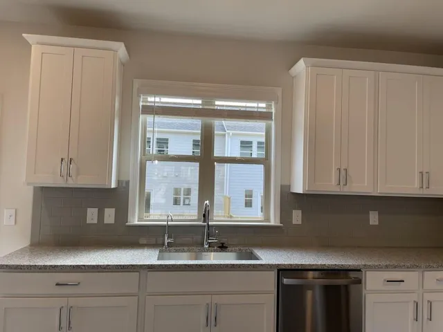 a kitchen with granite countertop white cabinets and a window