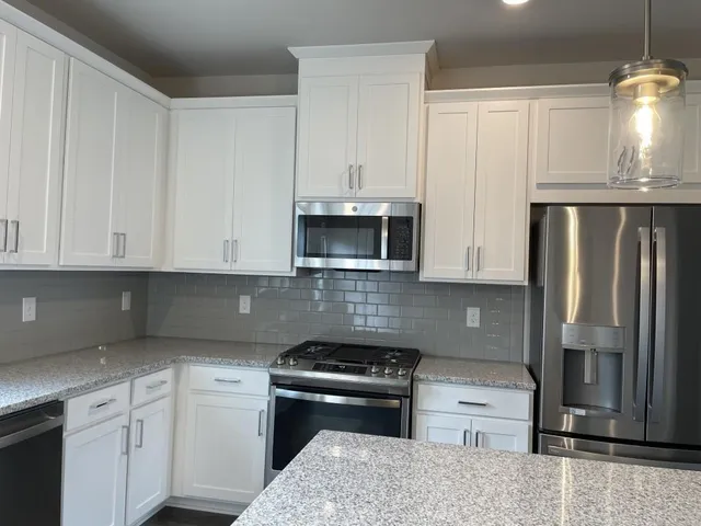 a kitchen with granite countertop white cabinets and stainless steel appliances