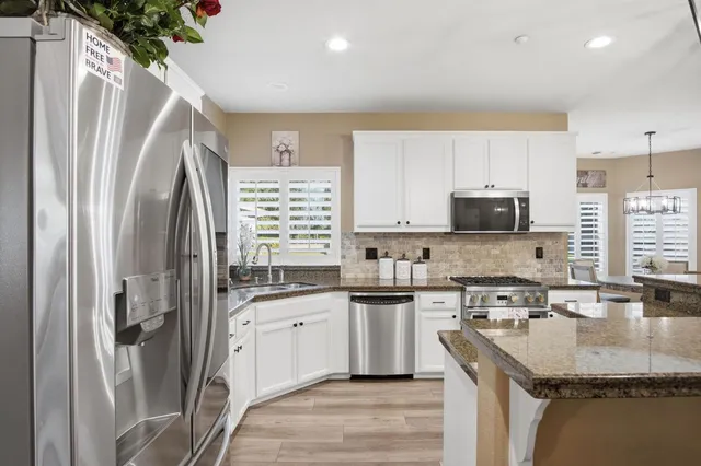 a kitchen with stainless steel appliances granite countertop a sink stove and refrigerator