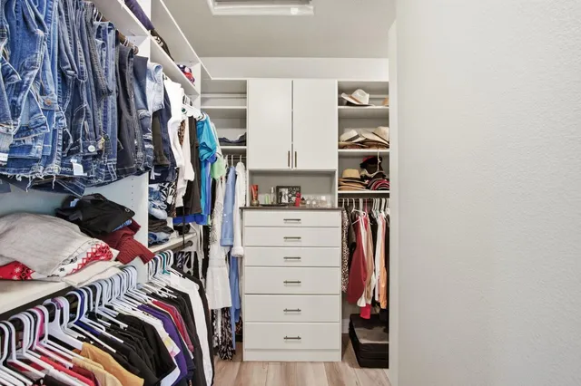 a view of walk in closet with clothes and shoes