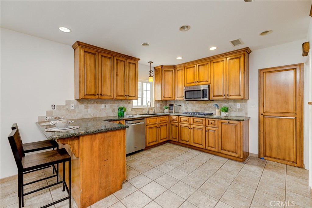3816 Chatwin Avenue Long Beach, CA 90808 - Photo 20 of 60 a kitchen with granite countertop wooden cabinets a sink a window and stainless steel appliances
