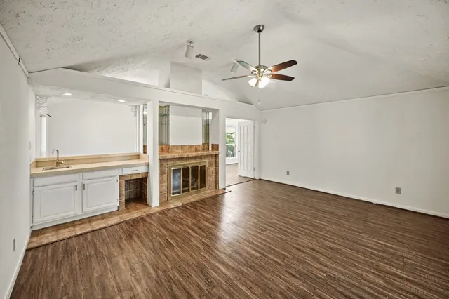 a view of a kitchen with a dishwasher a kitchen island hardwood floor and a ceiling fan