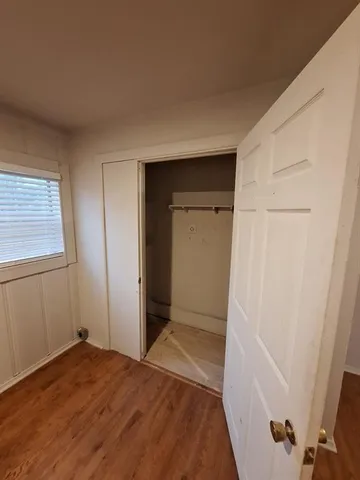 a view of hallway with closet and wooden floor