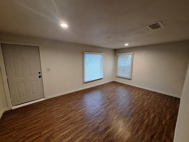 an empty room with wooden floor and windows