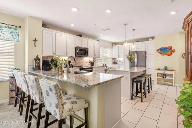 a kitchen with kitchen island a dining table chairs and a sink