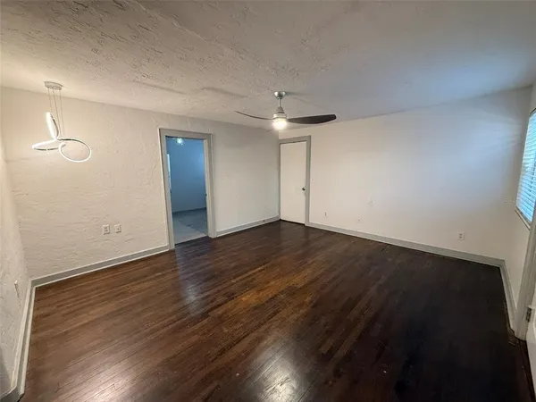an empty room with a chandelier fan and windows