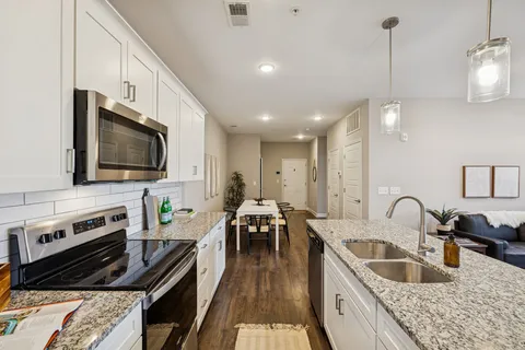 a kitchen with granite countertop a stove a sink a dining table and chairs