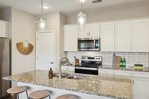 a kitchen with stainless steel appliances granite countertop a sink a stove counter space and cabinets