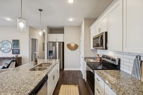 a kitchen with stainless steel appliances granite countertop a sink stove and refrigerator