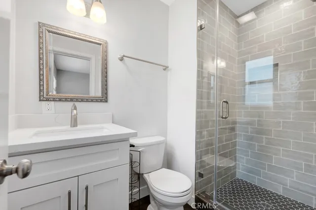 a bathroom with a sink a toilet a mirror and shower