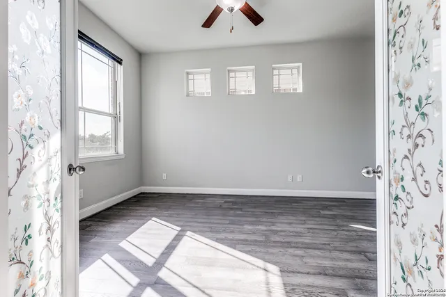 an empty room with wooden floor and windows