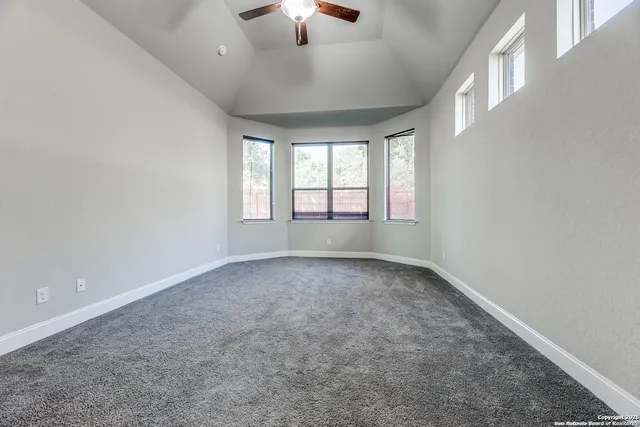 an empty room with windows and chandelier fan