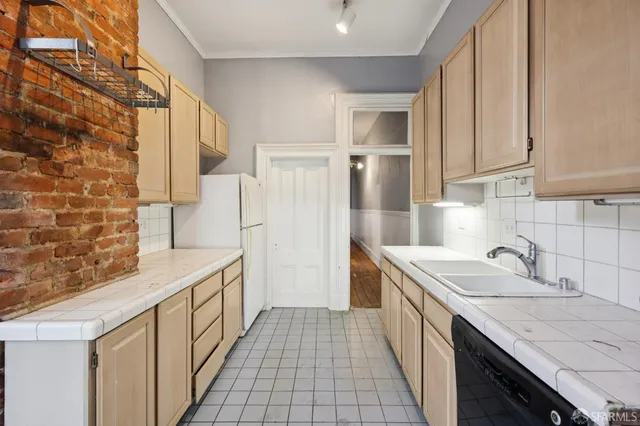 a view of an empty room with wooden floor fridge and a window