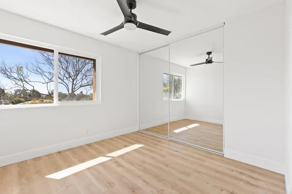 a view of empty room with wooden floor and fan