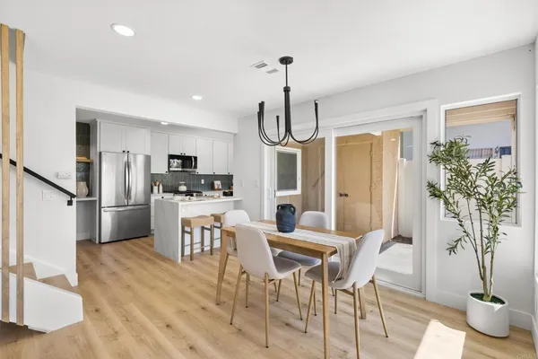 a kitchen with stainless steel appliances a dining table chairs stove refrigerator and cabinets
