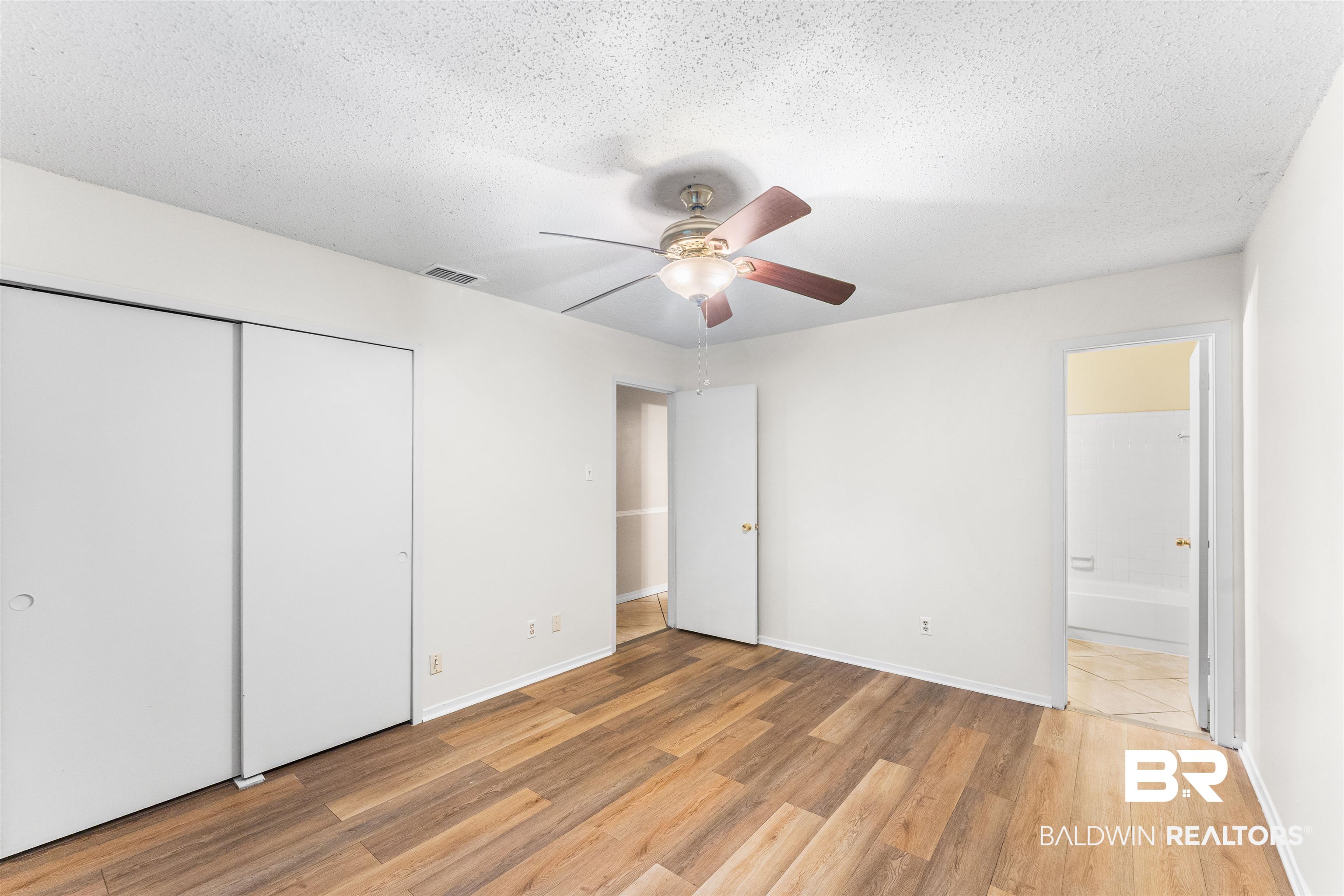 5551 Springer Court Theodore, AL 36582 - Photo 29 of 37 Unfurnished bedroom with light wood-type flooring, a ceiling fan, a textured ceiling, ensuite bath, and a closet