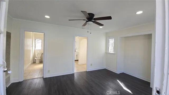 a view of empty room with wooden floor and fan