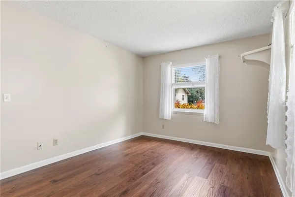 an empty room with wooden floor and window