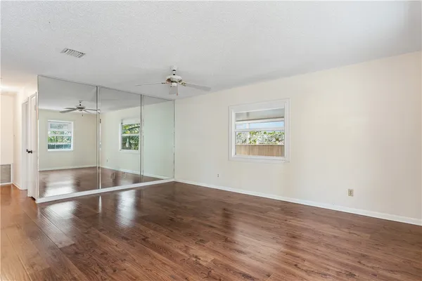 an empty room with wooden floor and windows