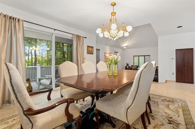 a view of a dining room with furniture a chandelier and large windows