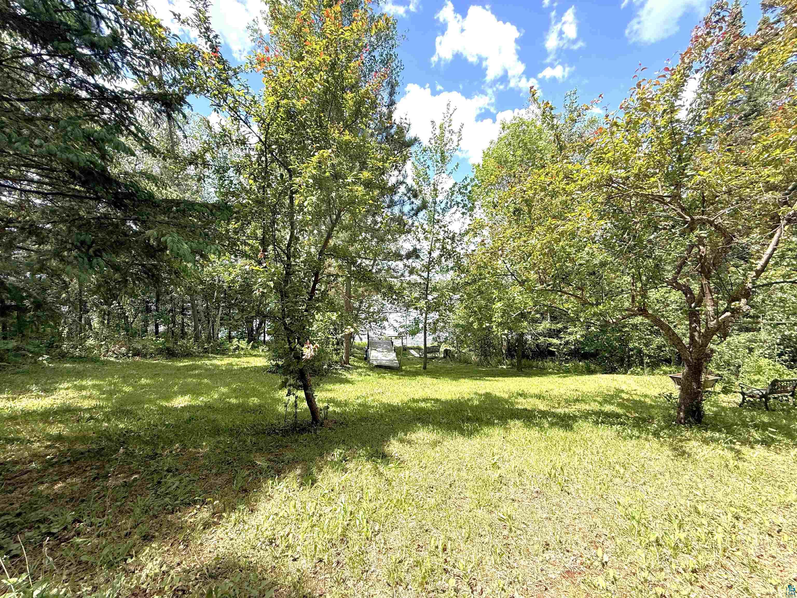 1787 North Bay Road Ely, MN 55731 - Photo 39 of 40 Expansive lawn surrounded by mature trees, featuring a distant body of water