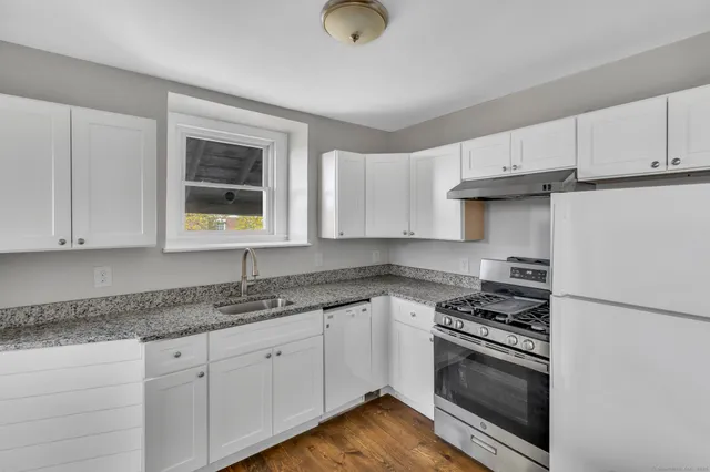 a kitchen with granite countertop cabinets stainless steel appliances and a window
