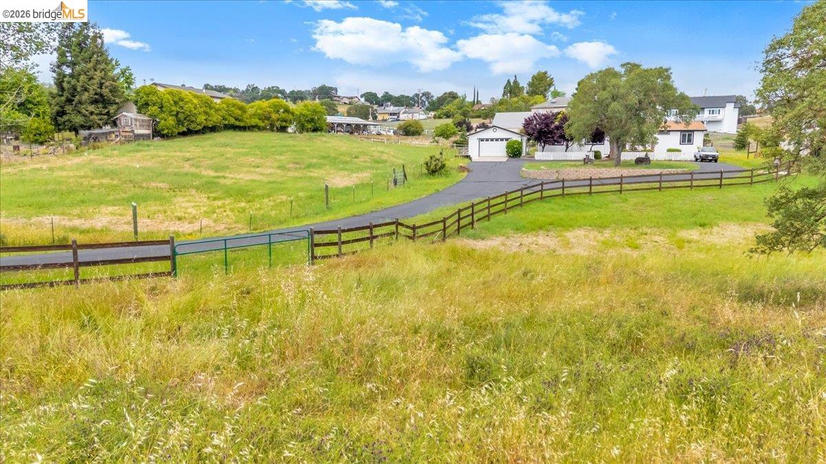 4419 Little John Road Copperopolis, CA 95228 - Photo 35 of 43 Expansive green acreage with a paved driveway and split-rail fencing