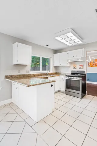 a kitchen with granite countertop a refrigerator stove top oven and sink