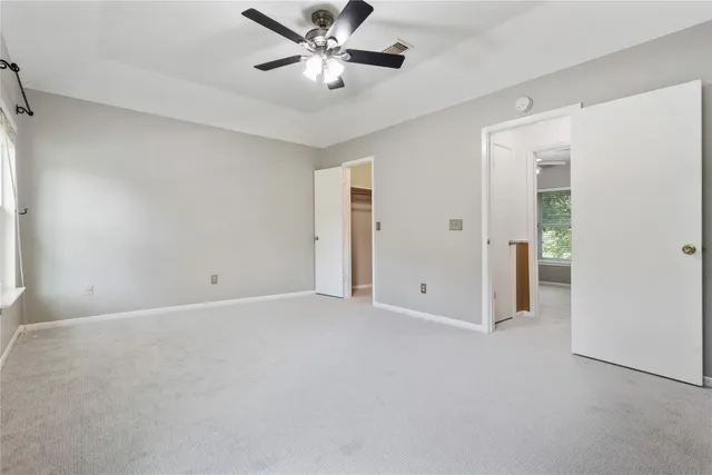 an empty room with a window and a fan