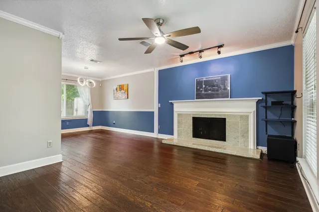 a view of an empty room with wooden floor fireplace and a window