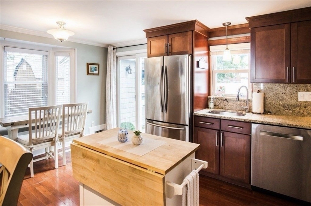 69 Keystone Street, Unit 1 Boston, MA 02132 - Photo 2 of 10 a kitchen with stainless steel appliances kitchen island granite countertop a refrigerator a sink a dining table and chairs with wooden floor