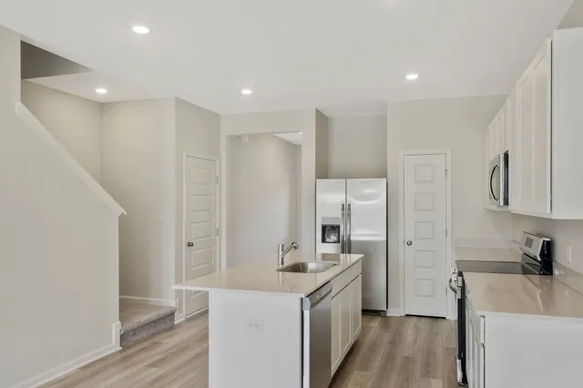 a kitchen with a sink a refrigerator a stove and wooden floor