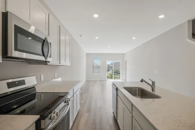 a kitchen with granite countertop a sink a stove top oven and refrigerator