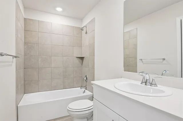 a bathroom with a bathtub shower sink vanity mirror and toilet